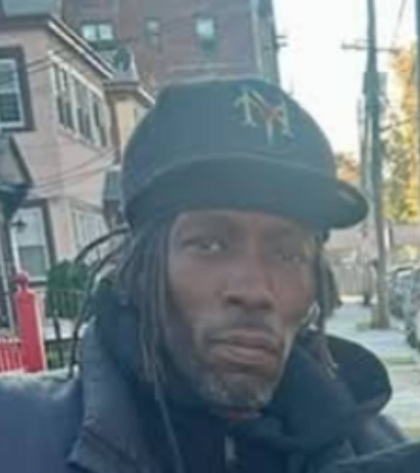 Close-up of MINDBENDA in an NY cap on a residential street
