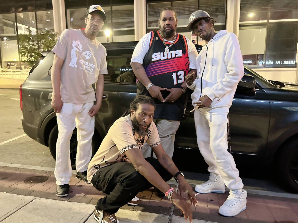 Nighttime group photo of MINDBENDA and the squad beside a dark SUV
